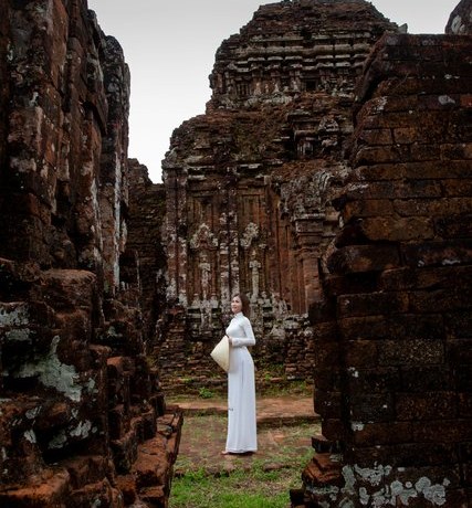 Visitor in an ao dai between the Cham temple towers at My Son